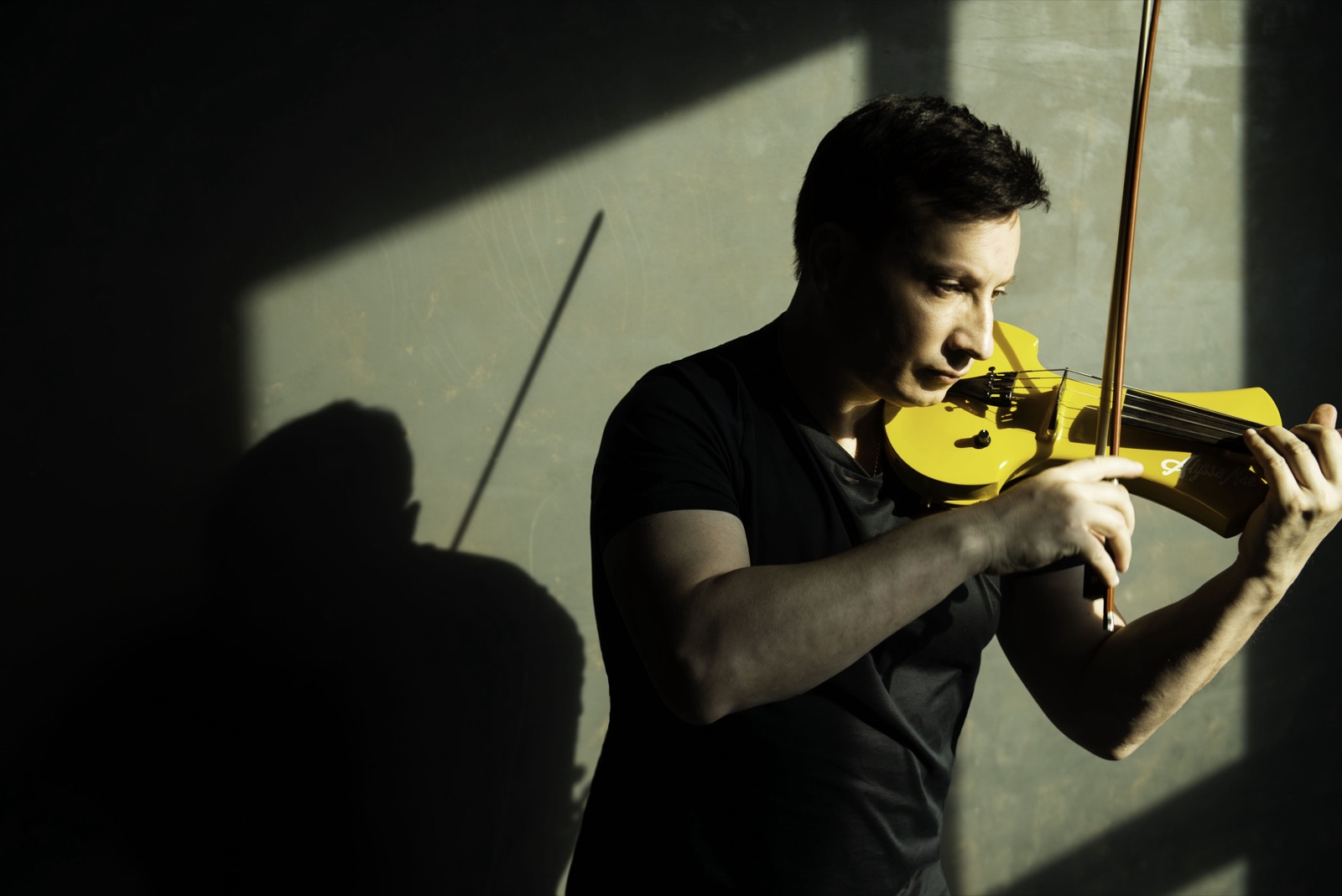 Fransoafran playing a yellow electric violin in a shaft of light